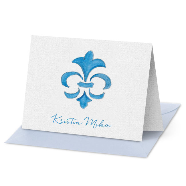 Folded Note Card featuring a blue fleur de lis image printed on white paper.